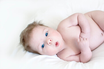 Cute happy 3 month baby boy lying on a white sheet