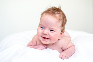 Laughing and happy baby boy drooling or burping laying on white background