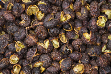 Macro full frame closeup of raw brown whole chinese sichuan timut pepper corns with citrus anise taste