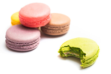 Bitten macaron and Various flavors of pastel macarons stacked against isolated on white background. Macarons is a delicate meringue-based cookie sandwich It is a dessert of French origin.