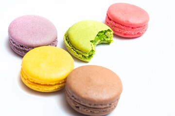 Bitten macaron and Various flavors of pastel macarons stacked against isolated on white background. Macarons is a delicate meringue-based cookie sandwich It is a dessert of French origin.