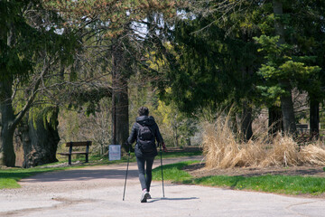 Active senior woman walking in the park with the hiking poles