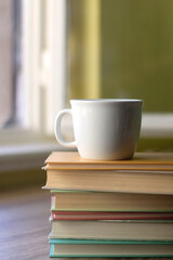 Stack of hardcover books and a cup of tea or coffee. Selective focus.