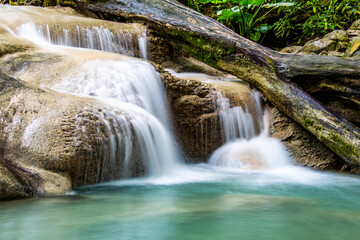 Fototapeta premium Waterfall and blue emerald water color in Erawan national park. Erawan Waterfall, Beautiful nature rock waterfall steps in tropical rainforest at Kanchanaburi province, Thailand
