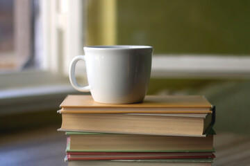 Stack of hardcover books and a cup of tea or coffee. Selective focus.