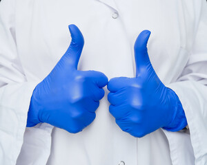 thumb up of doctor or nurse in protective medical gloves on white laboratory kittel background....