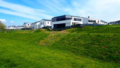Neubaugebiet mit neuen Wohnhäusern mit Flachdach im Grünen bei blauem Himmel