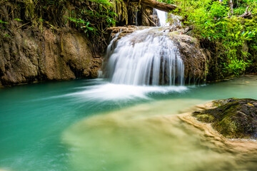 Obraz premium Waterfall and blue emerald water color in Erawan national park. Erawan Waterfall, Beautiful nature rock waterfall steps in tropical rainforest at Kanchanaburi province, Thailand