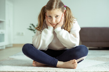 Portrait of beautiful teen girl bored or sad sitting alone on floor at home