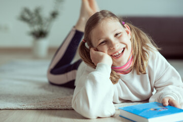 Happy smiling teen girl having fun with book on floor at home