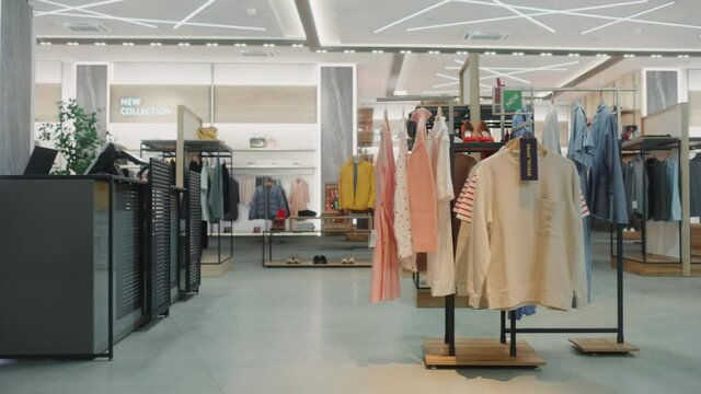 Shopping Clothing Store Interior. Modern Fashionable Shop, Clothes for Every Taste. Stylish Brand Design, Fashionable Colors, Quality Sustainable Materials. No People. Low Dolly Establishing Shot
