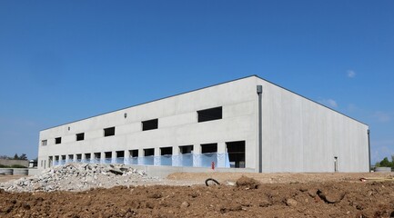 Large industrial warehouse made of prefab concrete blocks, under construction. The external walls are already finished - Powered by Adobe