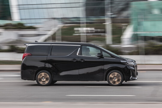 Fast moving Toyota Alphard on the city road. Gray van rides on street. Commercial auto in fast motion with blurred background. speeding in the city concept