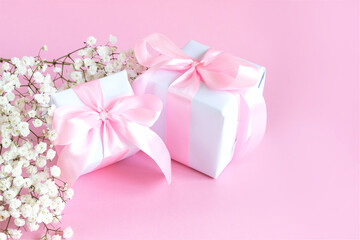 Gift box and a bouquet of blooming gypsophila on a pink background. Mother's day holiday concept. Copy space.