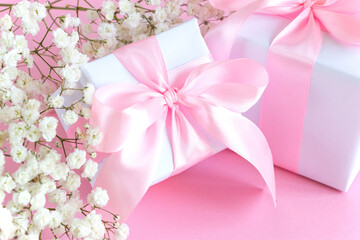 Gift box and a bouquet of blooming gypsophila on a pink background. Mother's day holiday concept. Copy space.