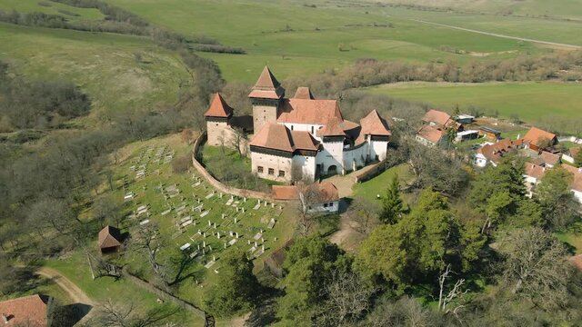 Aerial footage of a medieval fortified Church located in Viscri village, Brasov, Romania. Drone shot from a higher angle while circling around the fortress.