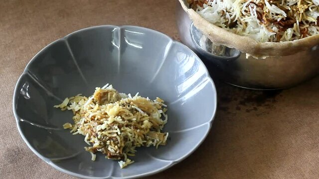 Serving Steamy hot Mutton Biryani. A dish cooked with spices layered between mildly spiced ghee rice with a generous sprinkle of caramelized onions and marinated Mutton