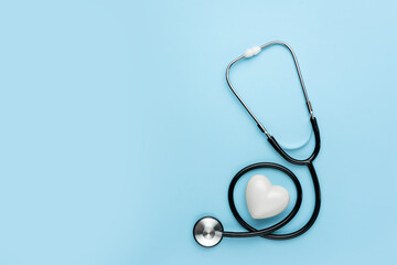Medical stethoscope and white heart symbol on a blue background with copy space.
