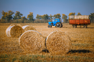 Hay bail harvesting in wonderful autumn farmers field landscape with hay stacks