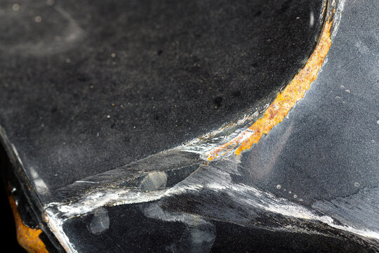 Zerbeultes Metall, staubig, mit Rostspuren. Wei&szlig;e Schleifspuren bilden ein Ypsilon.

