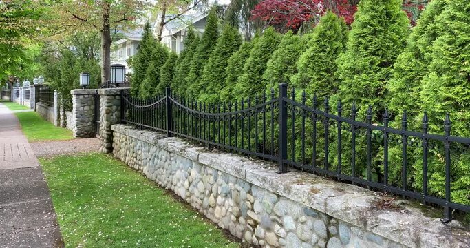 Establishing shot. Neighbourhood of luxury houses with street road, green fence and nice landscape in Vancouver, Canada. Blue sky. Day time on September 2020. Still camera view. 