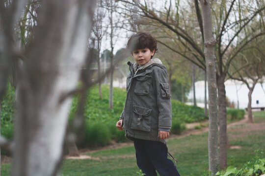 Spanish boy with jacket, walking and enjoying nature in a green forest