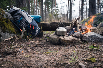 Backpack and Metal kettle on a campfire in the forest