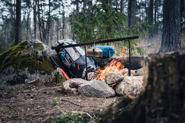 Backpack and Metal kettle on a campfire in the forest