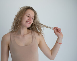 naughty girl touches a strand of her hair with her hand, she smiles cheerfully with a wide smile