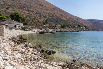 Fototapeta premium Stone beach and clear water in the bay of Porto Palermo, Albania