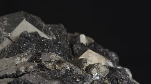 Pyrite dodecahedral crystals on hematite (also known as fool's gold or iron pyrite), isolated on a black background