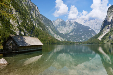 Fototapeta premium Traditional wooden boat house at Lake Obersee and mountain range in Berchtesgadener Land, Bavaria, Germany.