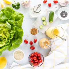 Top down view of various ingredients used to make salad and homemade salad dressing.