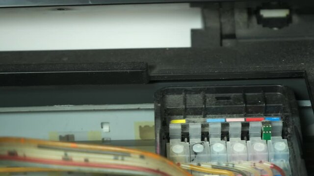 Continuous ink supply system is working in printer moving inside, closeup view. Printing new inkjet printer for launch, CISS. Small printer for use and printing at home, filled with only black paint.