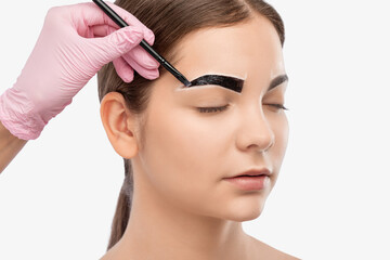 Make-up artist makes markings with white pencil for eyebrow and paints eyebrows. Professional makeup and facial care.