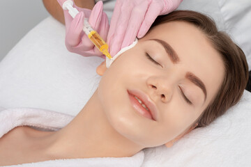 Cosmetologist does prp therapy on the face of a beautiful woman in a beauty salon. Cosmetology concept.