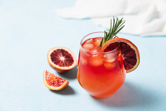 Delicious Blood Orange Cocktail On Light Blue Background. Summer Cocktails, Lemonade, Refreshing Drinks, Low Alcohol Mocktail Concept. Copy Space