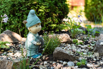 A gnome in the garden. Decorative sculptures. Landscape decor. A stone in the garden. Green garden....