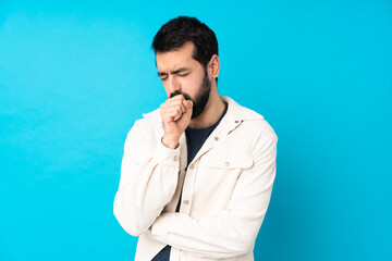 Young handsome man with white corduroy jacket over isolated blue background is suffering with cough and feeling bad