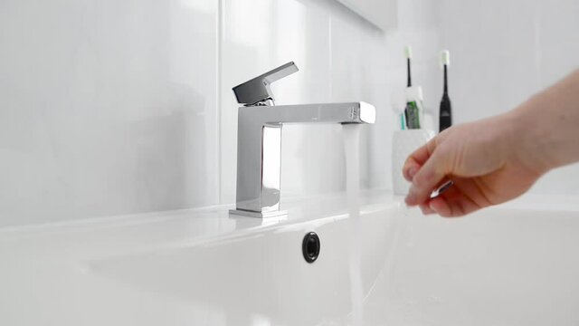 Flow of water pouring from chrome-plated faucet. Water flows from a faucet close-up. Running tap in bathroom. Water flowing from tap in bathroom. Plumbing sale concept. Chrome-plated faucet. 