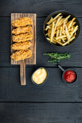 Breaded chicken wings on black wooden table, flat lay, with copy space
