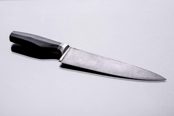 A large handmade hunting knife lying on a dark background