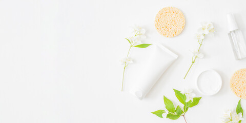 Flat lay composition with cosmetics and jasmine flowers on a light background