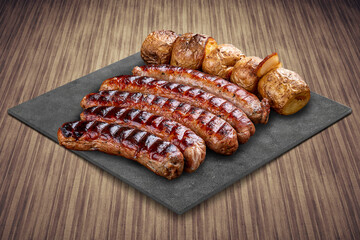 Handmade sausages with baked potatoes on a black board with a rustic timber background.