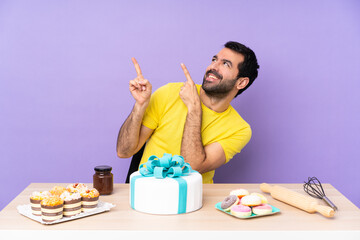 Man in a table with a big cake pointing with the index finger a great idea