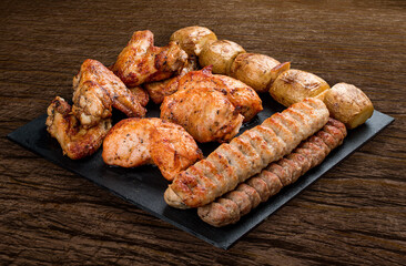 Stone board with different tasty cooked meat on wood background. Assorted meat