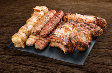 Stone board with different tasty cooked meat on wood background. Pork neck, potatoes, kebab