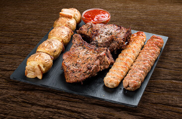 Stone board with different tasty cooked meat on wood background.  Veal kebab, lyulya, potatoes.