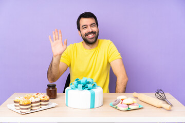 Man in a table with a big cake saluting with hand with happy expression