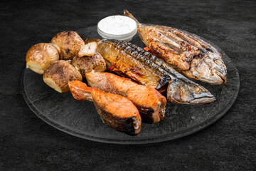 A selection of grilled gourmet meats on a rustic stone board. Assorted meat and fish